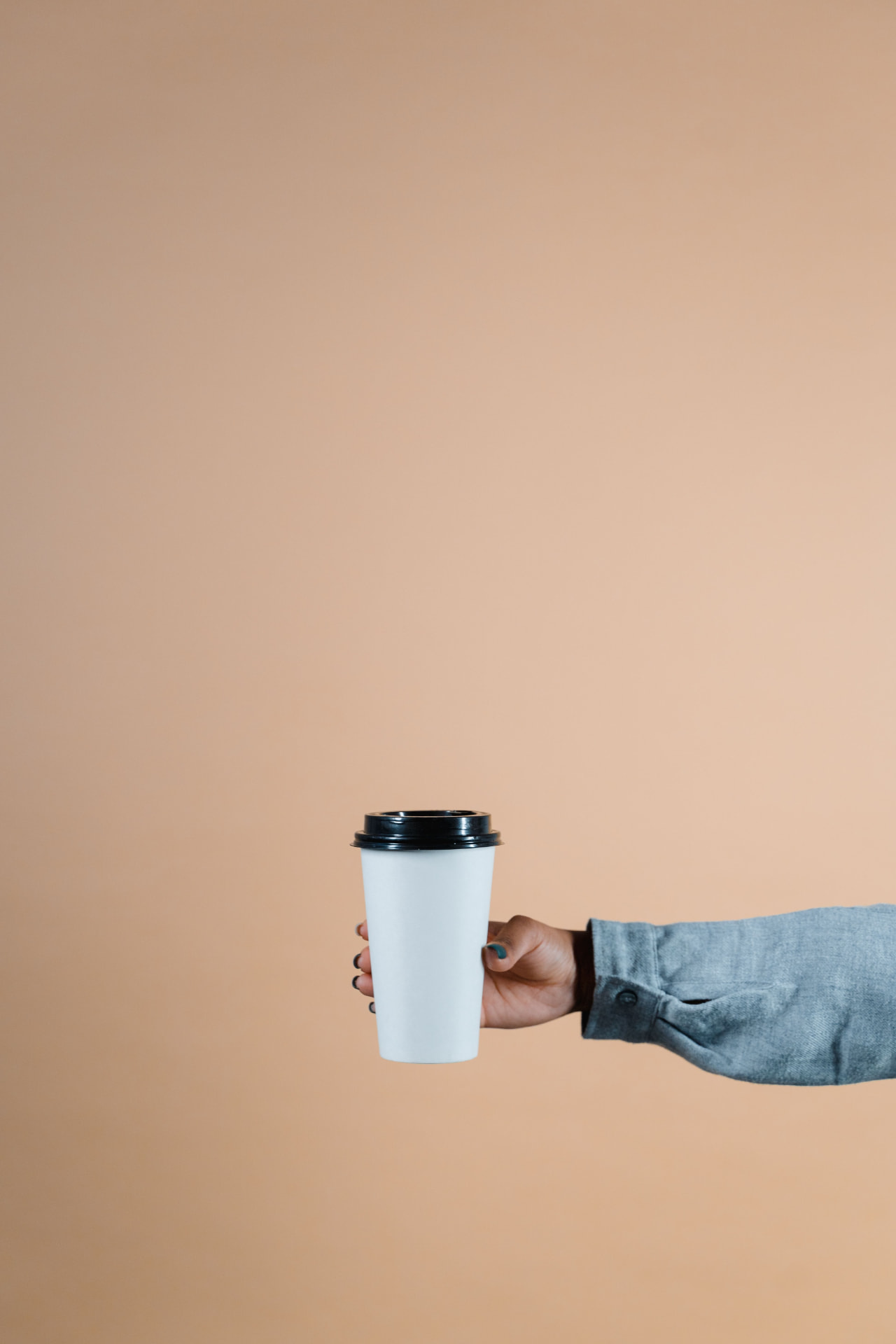 A hand holding a takeaway coffee cup